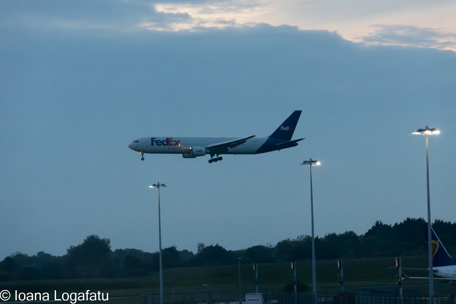 Plane descends low over runway at dusk